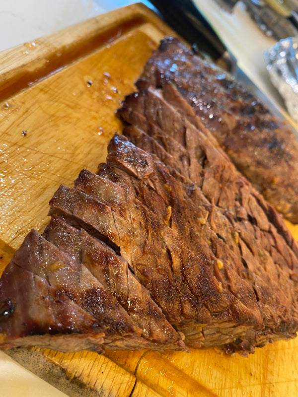 grilled marinated steak, sliced against the grain on a wooden cutting board