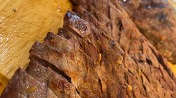 grilled marinated steak, sliced against the grain on a wooden cutting board